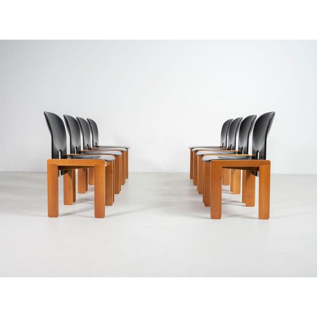 Set of eight 121 chairs with structure in wood, seat and back in foam rubber padding covered with black leather. Designed...