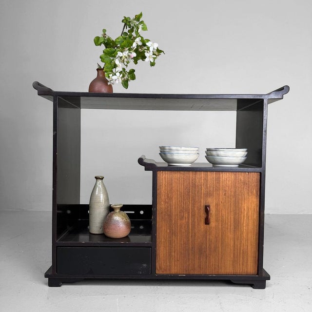 Stylish Japanese display cabinet from the 1920s, with an elegant asymmetrical layout and a dark lacquered finish. The...