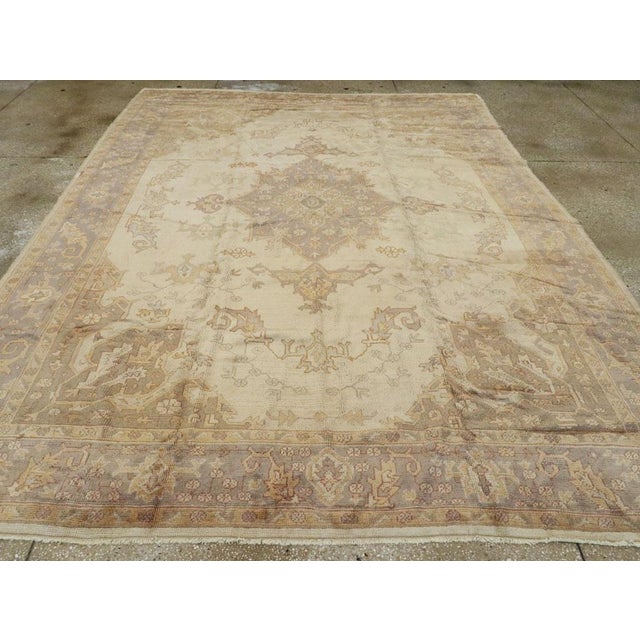 A vintage Turkish Oushak room size carpet. The pearl ground of this Turkish room size carpet displays sawtooth, curved...