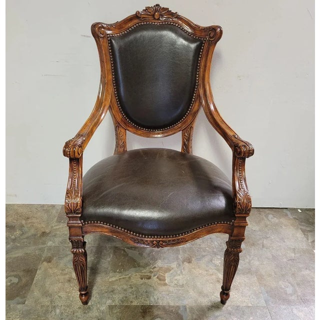 A stunning Theodore Alexander hand carved mahogany accent chair. Upholstered in brown leather with brass nailhead...