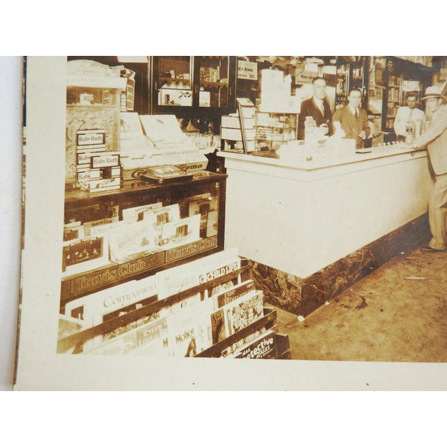 Antique silver gelatin photograph of the interior of a store and soda fountain. Stuffed full of cigars, candy, signs, Dr....
