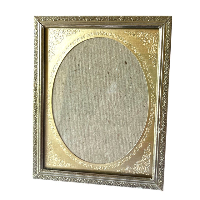 A beautifully detailed vintage silver tone picture frame featuring an elegant oval gold matte opening surrounded by finely...