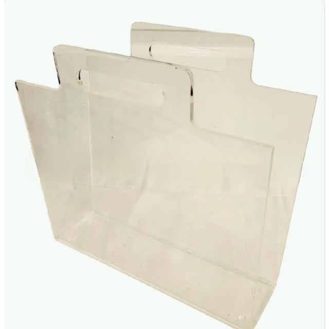 A vintage lucite magazine stand with simple lines and tiny ball feet.