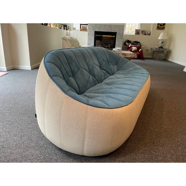 Designer Ligne Roset Ottoman sofa has a unique shape with quilted teal blue upholstery and a light cream base. This high-...