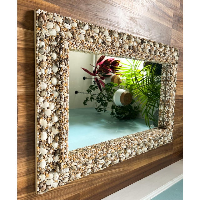 A striking vintage shell-encrusted mirror featuring an intricate, densely layered border made from natural seashells in...