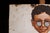 Single-sided porcelain enamel trade sign featuring a stylized portrait of a young boy wearing round spectacles, rendered...