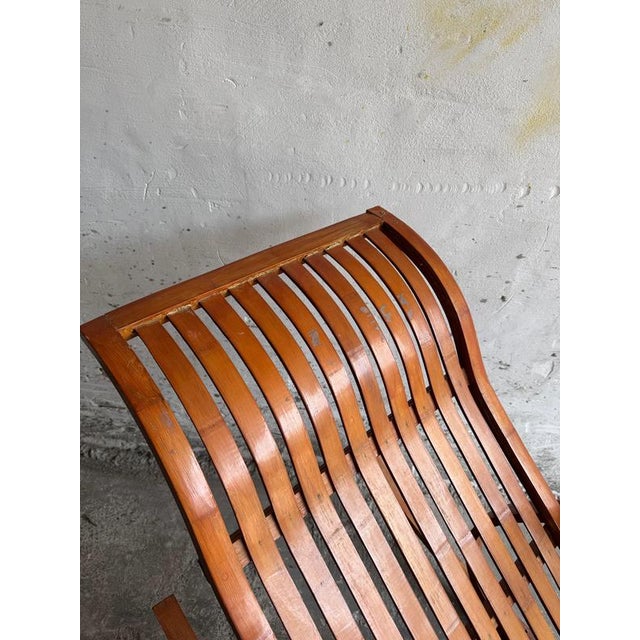 A striking vintage wooden rocking chaise longue featuring a curved slatted seat and distinctive circular rocker frames....