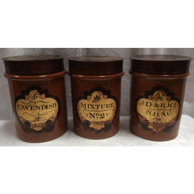 Excellent rare set of three antique red Stoneware Tobacco Jars from England with patinated Tole Canister lids. The metal...