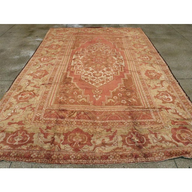 An antique Turkish Oushak room size carpet. An enormous, bold reversing turtle palmette border on a salmon-buff ground...