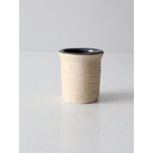 This small vintage studio pottery vase features a natural, unglazed exterior that highlights the texture of the clay. The...