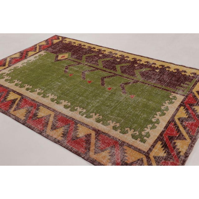 Hand-knotted in wool, this vintage 7x10 Turkish rug from circa 1950–1960 features an arresting geometric composition in...