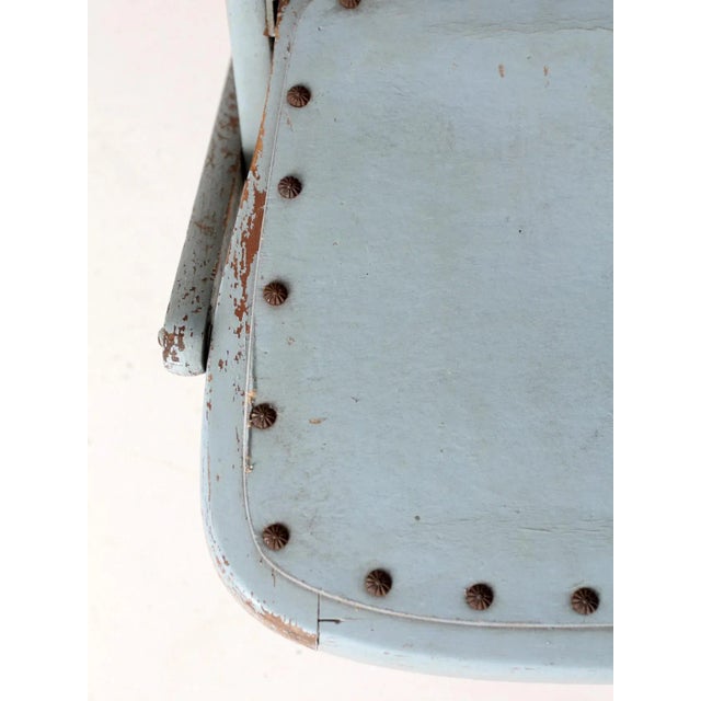 An antique wooden folding chair featuring a robin’s egg blue painted finish, a classic spindle back, and a seat accented...