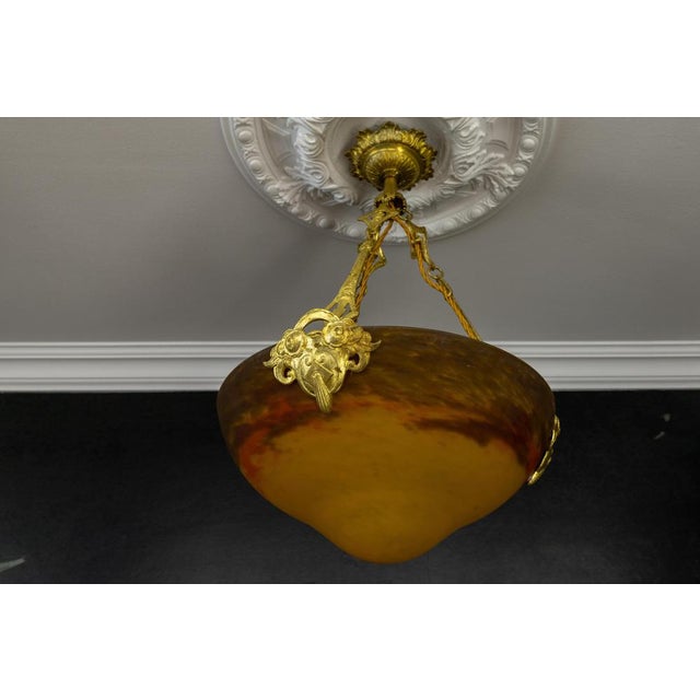 A refined french art nouveau pendant by muller frères lunéville, featuring a richly toned pâte de verre glass bowl and...