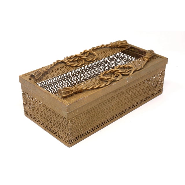 A vintage antique gold-colored metal tissue box holder,with rope and tassel design, and punched pattern in the box. Good...
