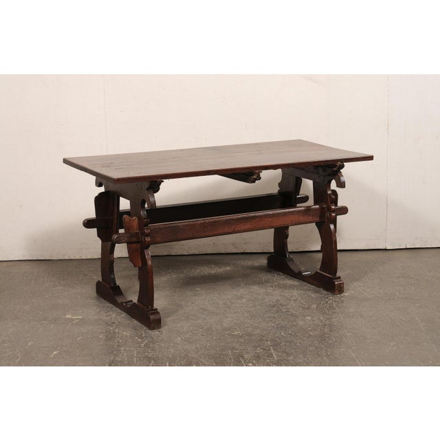 A French oak wood trestle table from the early 19th century. This antique oak wood table from France features a...