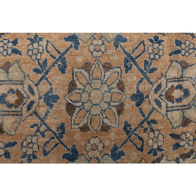 An early 20th century Persian Tabriz carpet, the abrashed rust field with an allover lattice of palmettes, flowerheads and...