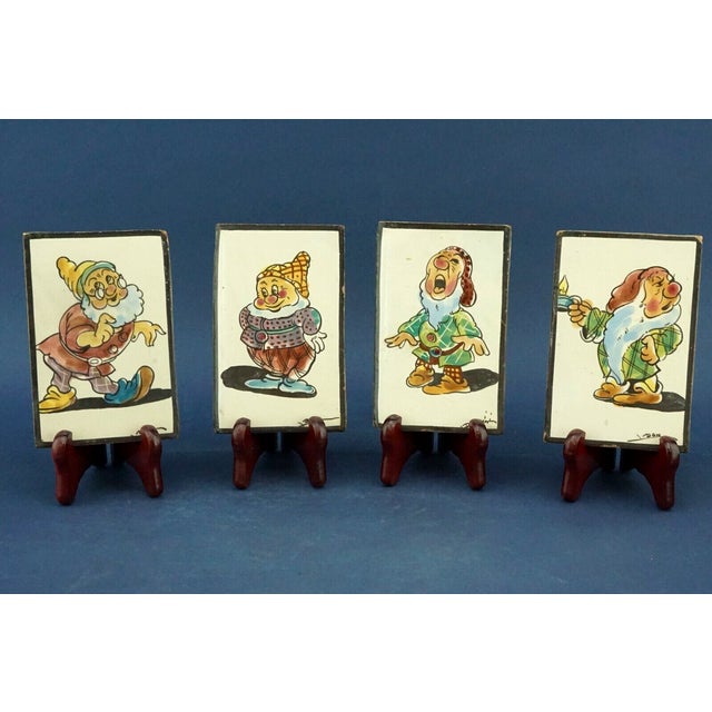 A wonderful lot of four hand-decorated majolica tiles depicting four of the seven famous dwarves from disney's "snow...