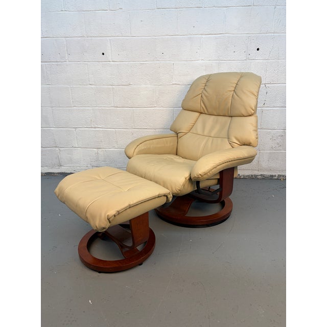 Relax in comfort with this stylish beige leather recliner chair and matching ottoman. The chair features a high, cushioned...
