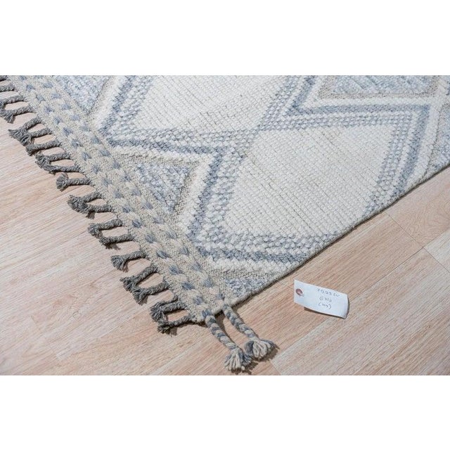 This hand-knotted pile wool rug features a primary color palette of ivory, beige, and cream white tones. It is a genuine...