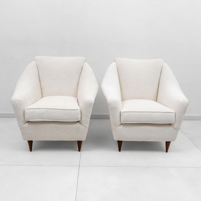 A pair of Italian armchairs produced in the 1950s. The armchairs have been completely restored and upholstered in cream-...