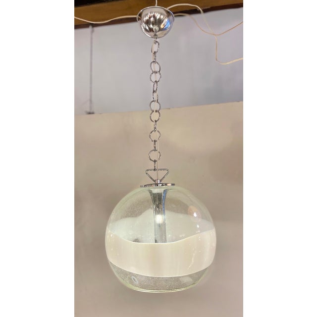 Beautiful italian pendant lamp made of a clear murano glass globe with bubbles and a white line hanging on a chrome...