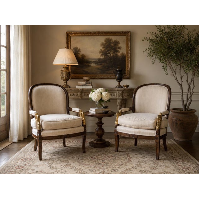 An elegant pair of vintage French Empire-style armchairs featuring beautifully carved swan-form armrests highlighted with...