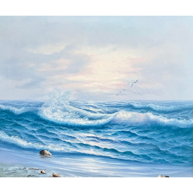 A luminous vintage coastal seascape oil painting depicting rolling ocean waves breaking along a rocky shoreline beneath a...