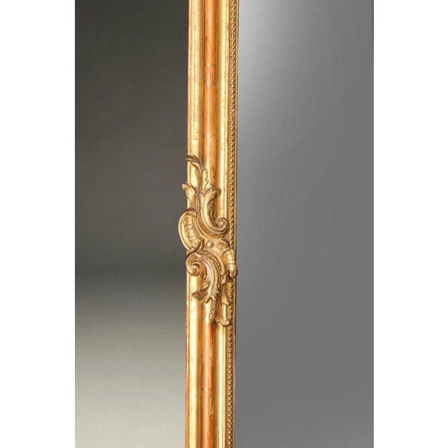 19th century French Louis XV style gilded mirror with beveled glass, featuring a hand-carved wood frame finished in gesso...