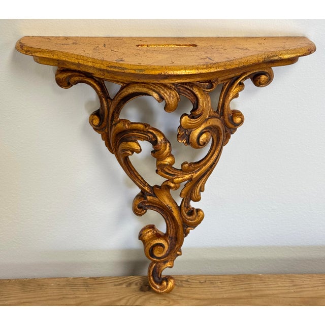 Decorative vintage Italian Florentine style wall shelf. Features a gilt leaf surface with carved wooden floral scrolls...
