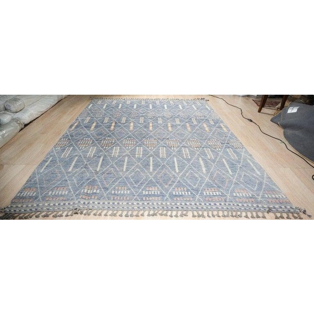 This blue wool rug features a hand knotted pile construction and reflects the distinct style of a Berber carpet. Sourced...