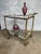An elegant French brass and glass bar cart from the 1950s. The brass frame has a stylized bamboo motif and is supported on...