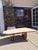 Vintage coffee table with irregular rounded triangular top in travertine stone. Top has a honed finish with visible...
