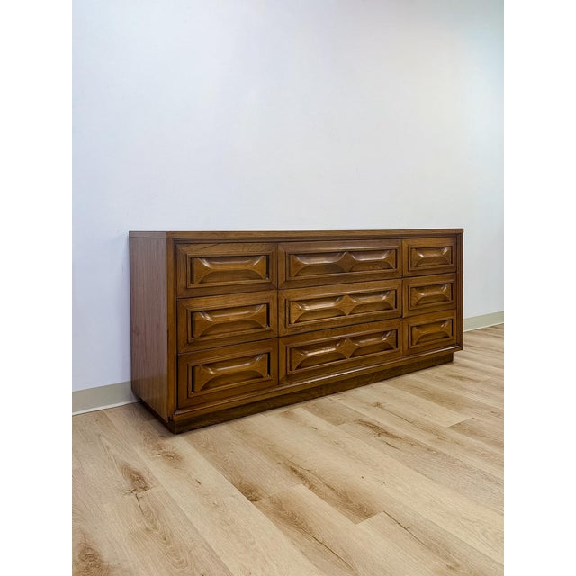 This vintage mid-century dresser stands out for its distinctive bowtie inlay detailing, a hallmark joinery technique...