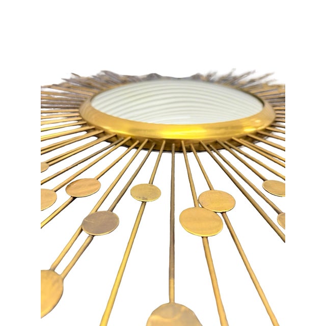 A striking Mid-Century Modern style convex sunburst mirror crafted from solid metal with an antique brass finish....