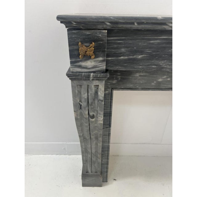 Napoleon iii style fireplace in "bleu turquin" marble two console-style jambs with recessed fluting front panel decorated...