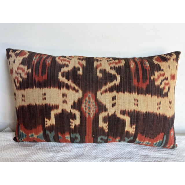 This vibrant 1850 Ikat pillow features bold abstract motifs in warm and earthy tones. The traditional pattern, rendered in...