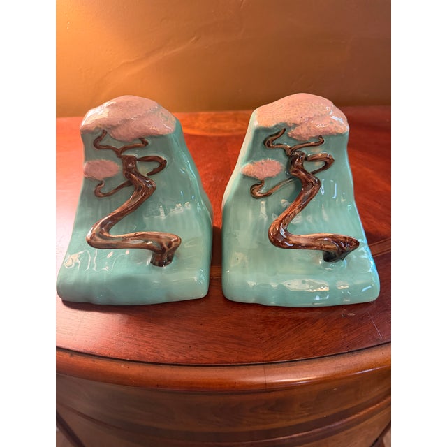 Add a vibrant touch of mid-century elegance to your shelves with a flawlessly matched pair of authentic Roseville Art...