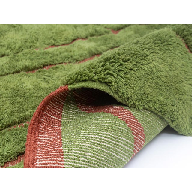 Earth and fire, united in wool. This stunning hand-knotted Moroccan rug pairs a deep, lush olive green field with bold...