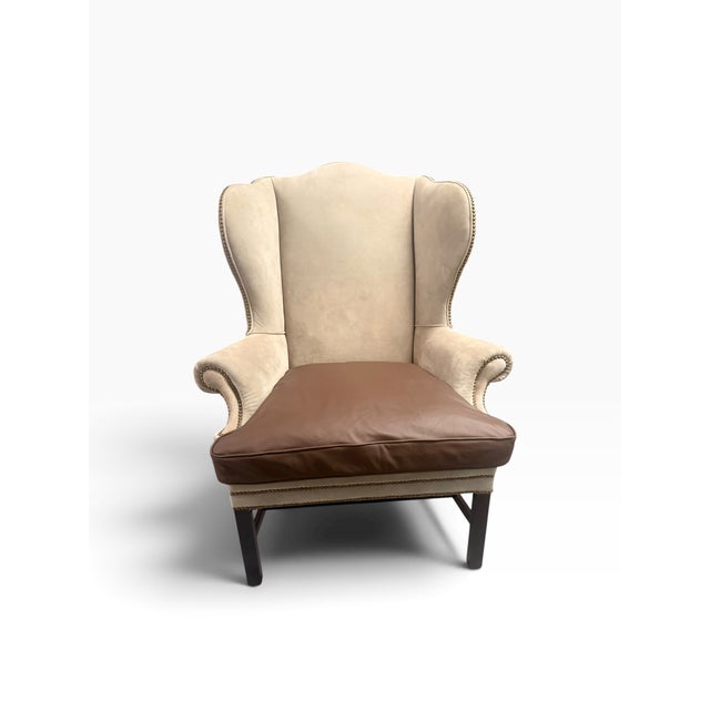 A handsome Ralph Lauren Home Devonshire wingback chair, upholstered in luxurious neutral suede and detailed with classic...