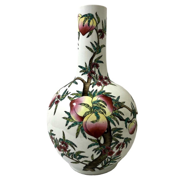 This pair of Chinese porcelain vessels is a striking example of Famille Rose (Fencai) "Nine Peaches" vases, modeled after...