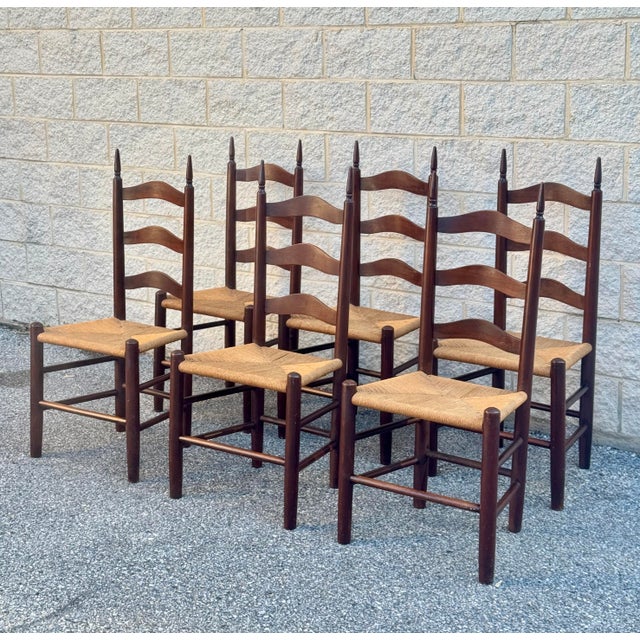 French Provincial dining chairs with shaped ladderback frames, handwoven rush seats, and turned finial posts. Solid wood...
