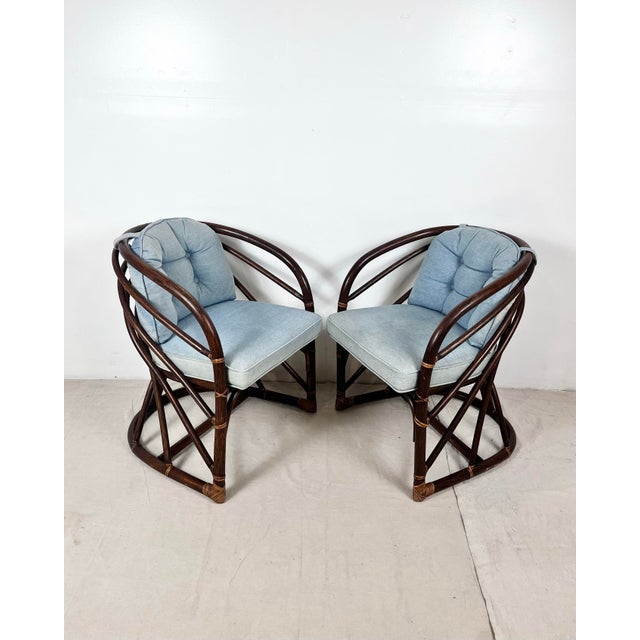 Vintage pair of round back rattan lounge chairs. Curved frames with bent rattan details. Upholstered seats with removable...