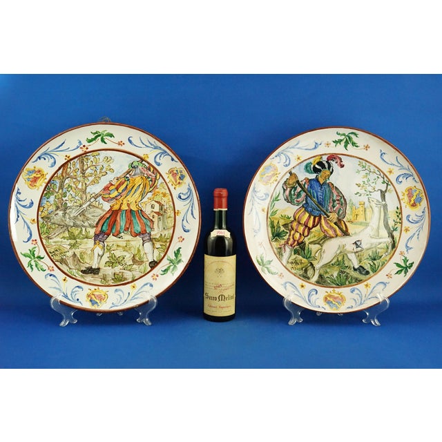 A wonderful pair of large glazed and vitrified ceramic plates, entirely hand-decorated with two different scenes in the...