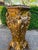 A dramatic 1990s Italian Baroque-style pedestal, richly decorated in a gold finish with a dark marble-effect top. This...