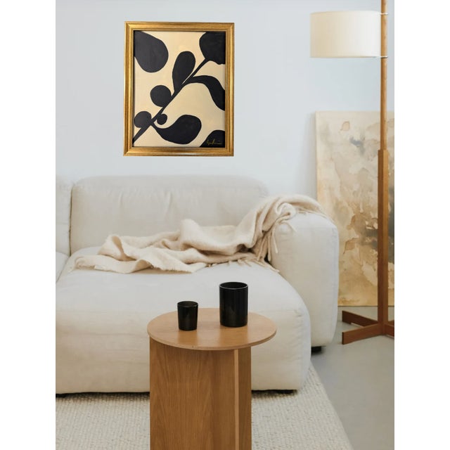 A bold, modern botanical-style painting featuring abstract black leaf and branch forms set against a warm cream...