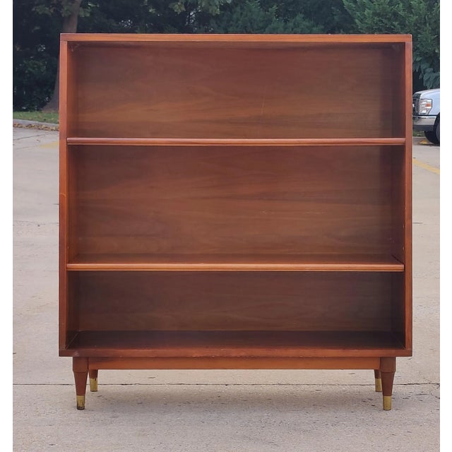 American Mid-Century walnut bookcase with two shelves (one of which is adjustable in height) in a rectangular cabinet,...
