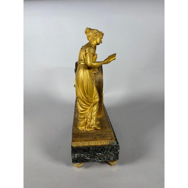 A French Empire period allegory of knowledge clock, circa 1800. Made of mercury-gilt bronze and polished with agate, it...