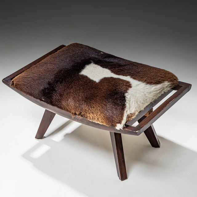 Lounge chair by Paul László with matching ottoman and dark-stained wooden frame. Both chair and ottoman are upholstered in...