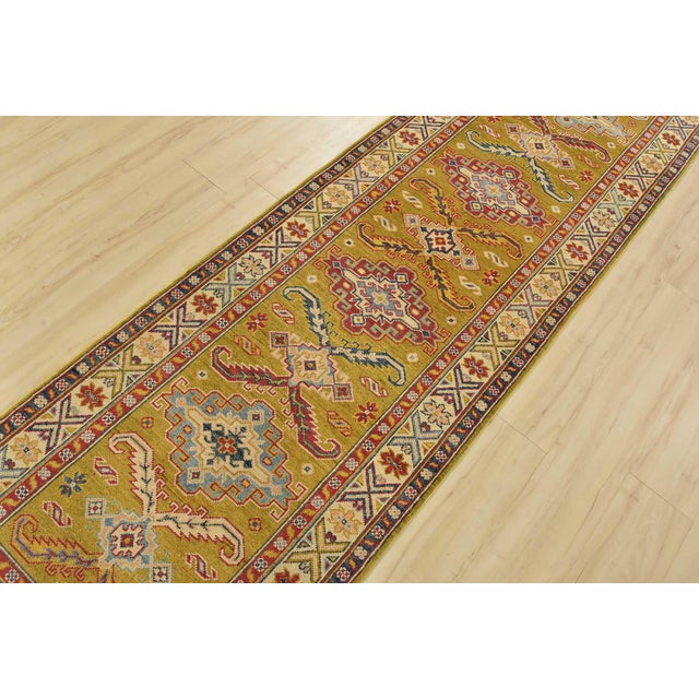 A tribal Caucasian Kazak runner hand-knotted with fine wool on a cotton foundation. This rug features a row of geometric...