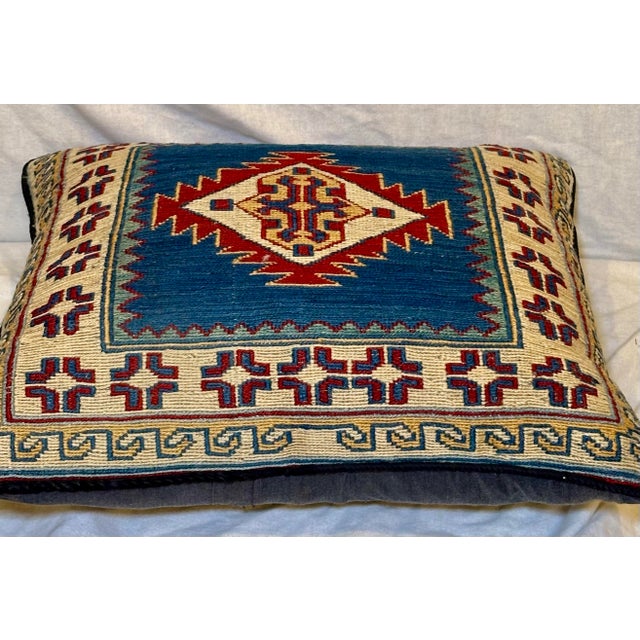 A handwoven kilim textile accent pillow featuring a bold geometric medallion within a richly patterned border, executed in...